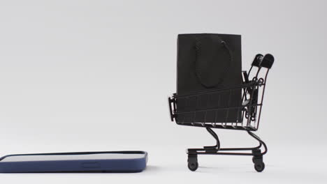 vídeo de un teléfono inteligente, una bolsa de compras y un carrito con espacio de copia sobre un fondo blanco