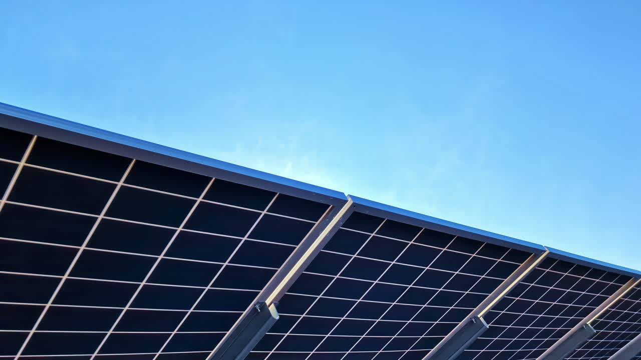 Close-up of solar panels tilted toward the sun against a bright blue sky background