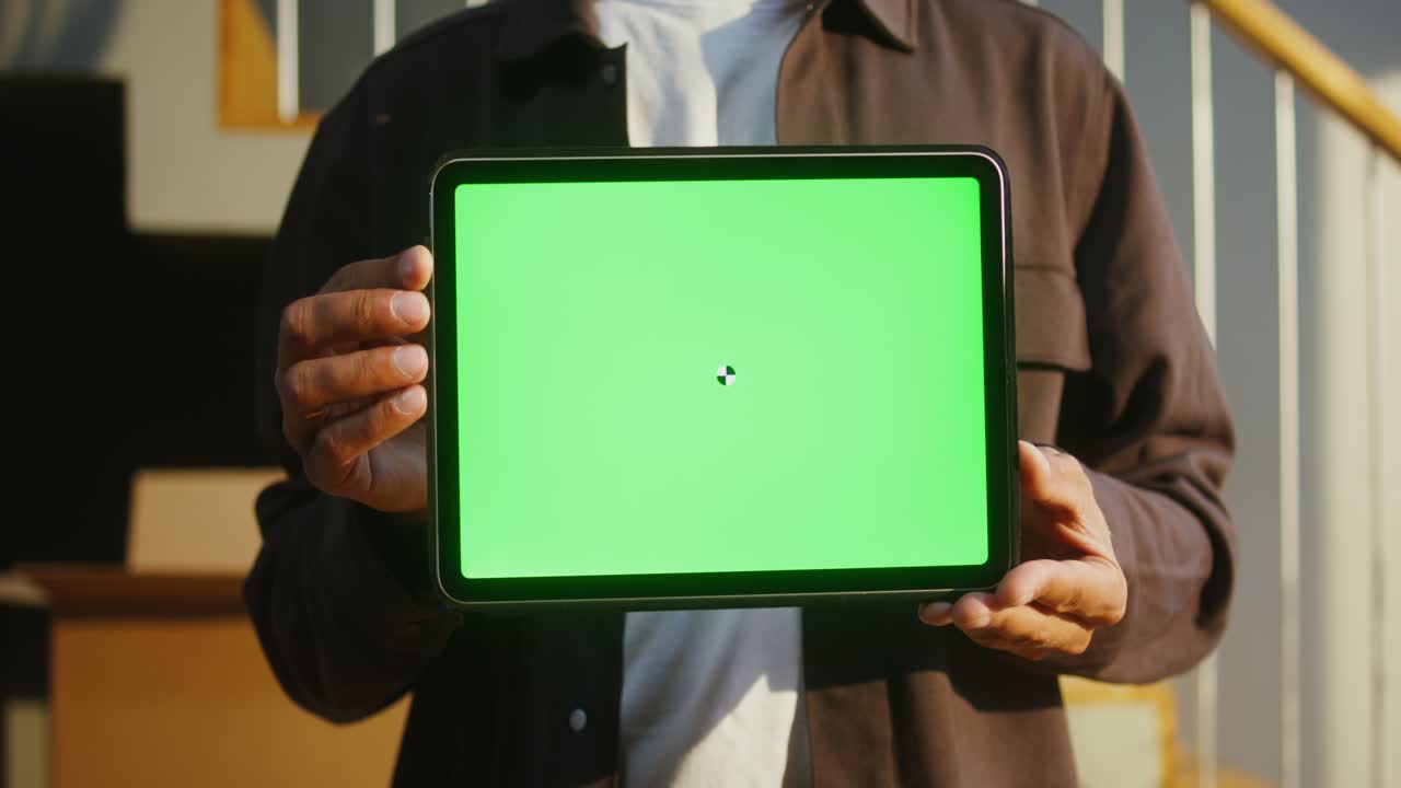 persona que sostiene la tableta con pantalla verde