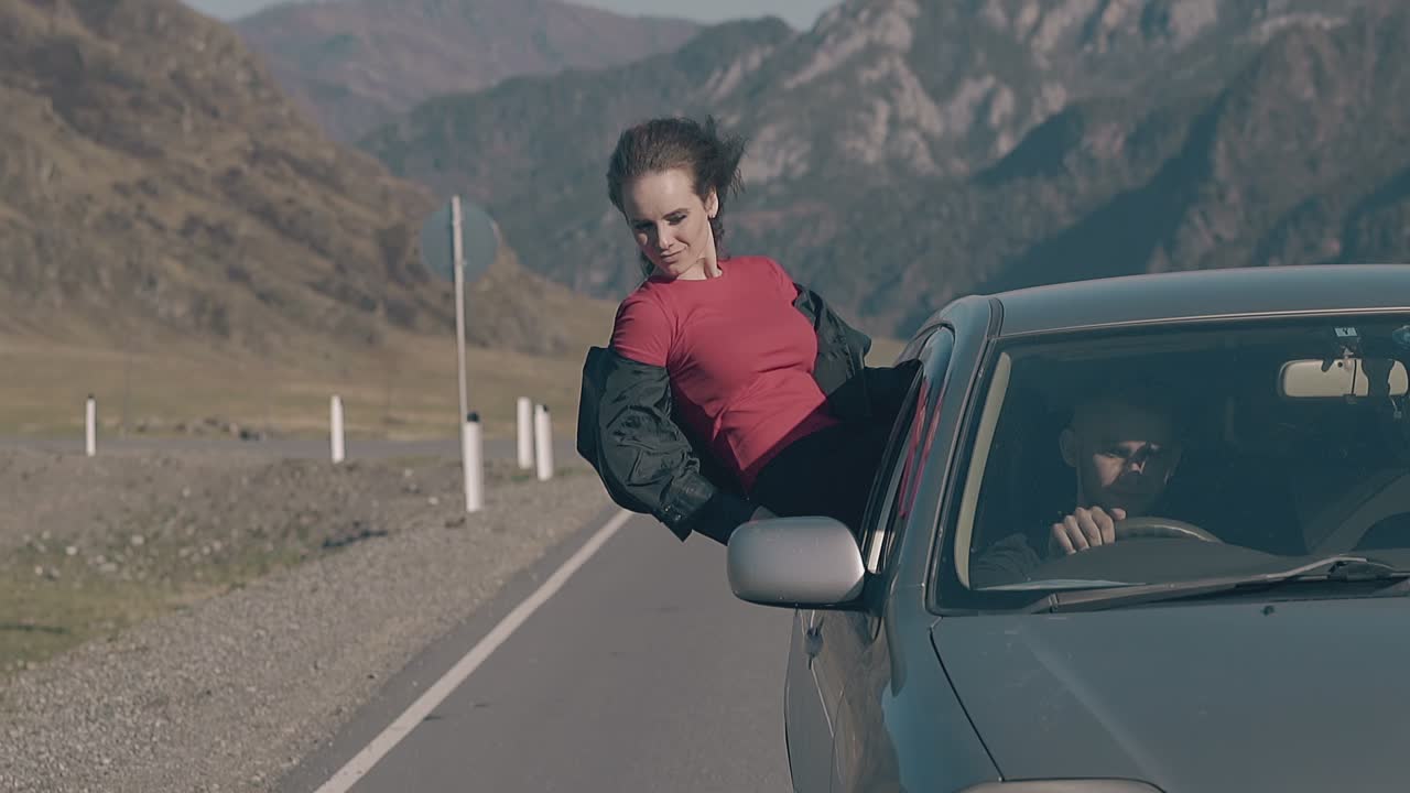 el viento juega con el cabello de una morena relajada conduciendo en un coche