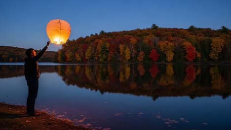 A Serene Moment by the Lake: Launching a Floating Lantern Against a Backdrop of Autumn Colors and Peaceful Reflections at Dusk