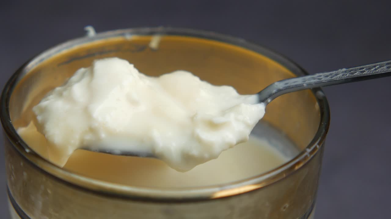 primer plano de una cuchara de yogur blanco en un vaso