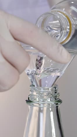 pouring vinegar into a bottle with funnel