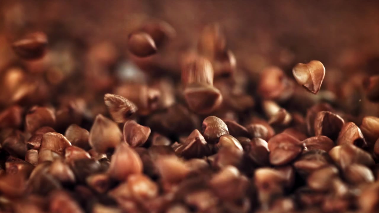 Chicchi di grano saraceno crudo che cadono e si accumulano al rallentatore.