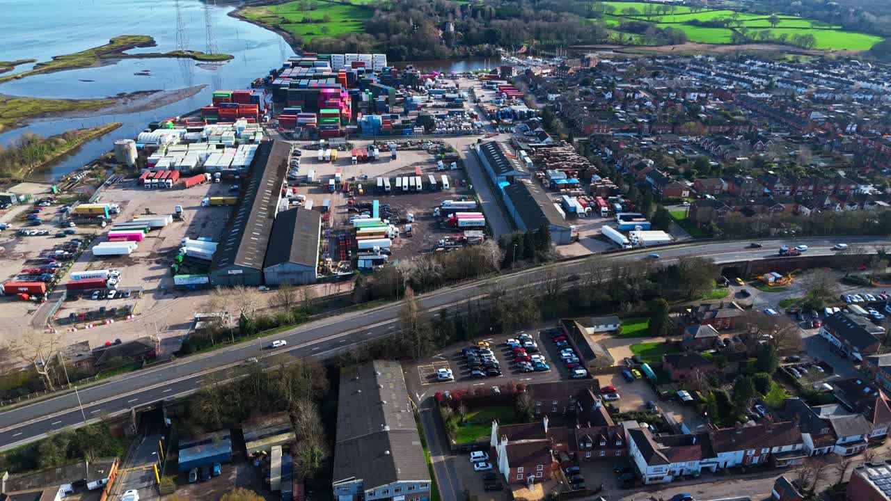 Pengambilan gambar panorama udara di atas pinggiran kota Totton di sebelah barat sungai di Southampton, Inggris, dengan mobil-mobil yang melaju di jalanan ramai dan sinar matahari yang memantul di air sungai biru dengan perahu-perahu di atasnya pada musim dingin.