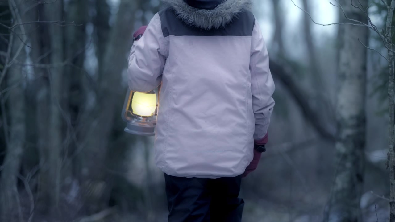 Anak dengan lentera tersesat di hutan pada malam hari. Pengambilan gambar detail dekat.