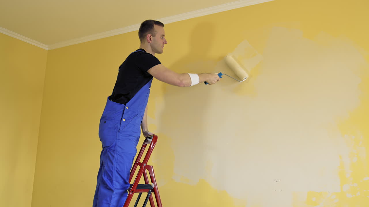 Painting wall with roller brush. Young man painting wall, using roller brush