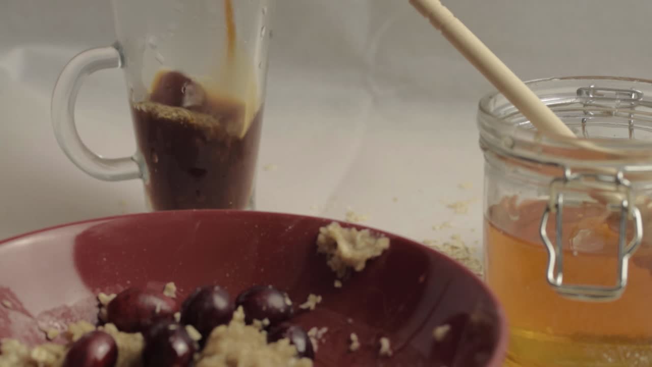 Pouring fresh coffee with healthy breakfast of porridge, honey and cranberries medium shot