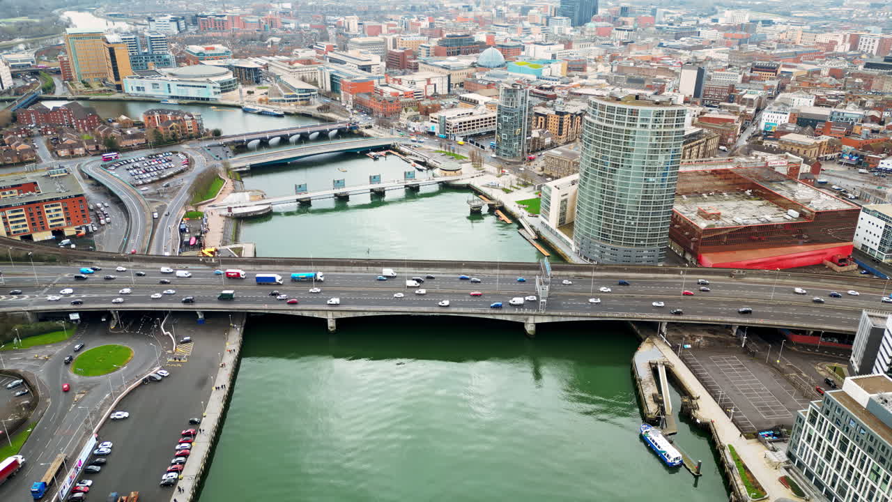 Aerial drone view of cars driving over the buildings surrounding River Lagan in Belfast, Northern Ireland