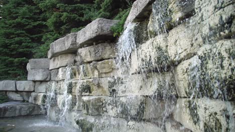 Primer-Plano-Panorámico-De-Una-Cascada-Y-Un-Muro-De-Piedra-Decorativo-Del-Jardín