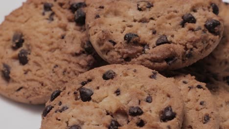 Primer-Plano-En-Un-Pequeño-Lote-De-Galletas-Con-Trocitos-De-Chocolate-Girando,-Fondo-Blanco