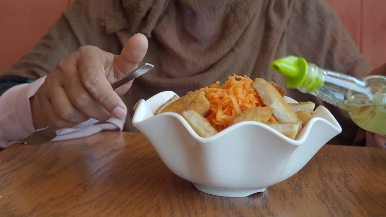 una mujer comiendo una ensalada con pollo y zanahorias