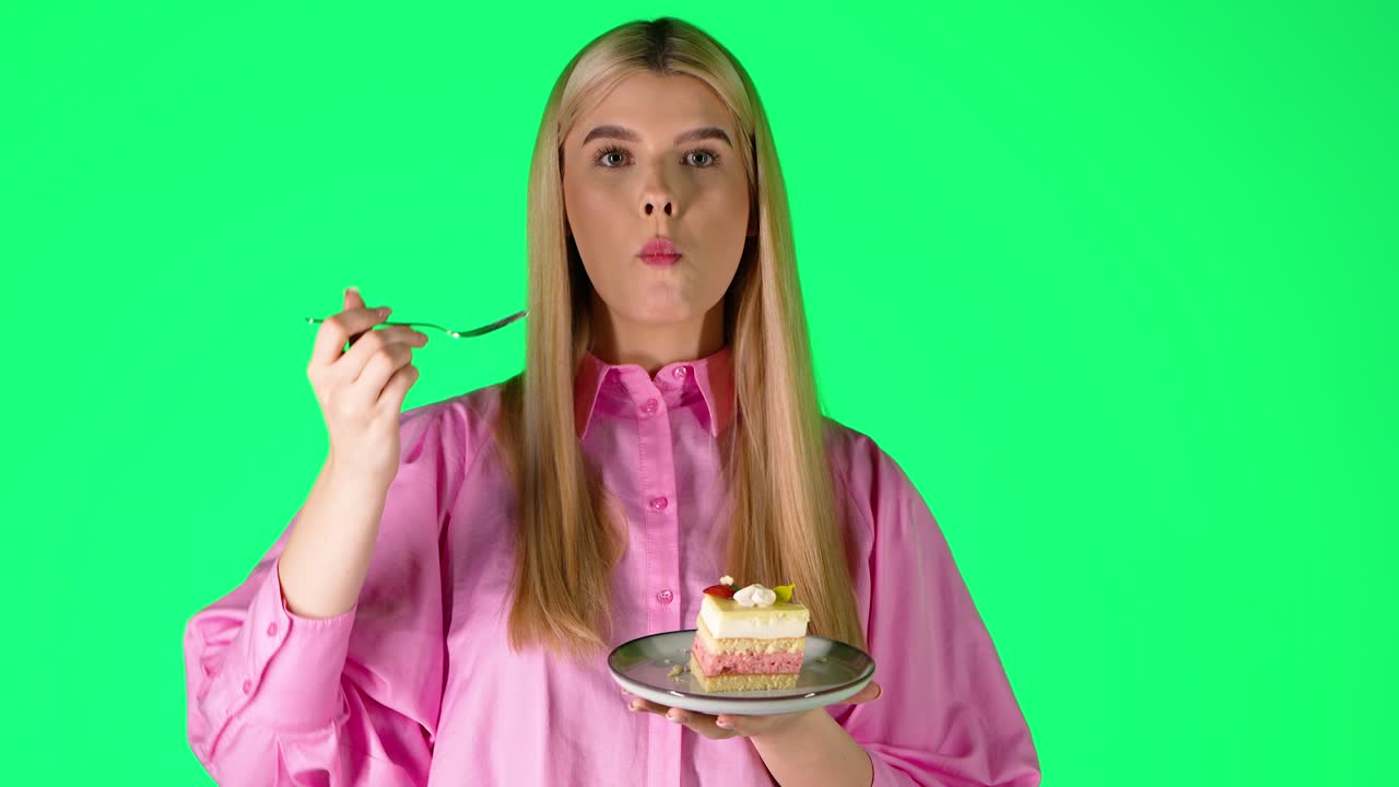 Pretty Blonde Woman Eating Delicious Cake, Studio Portrait With Green Background
