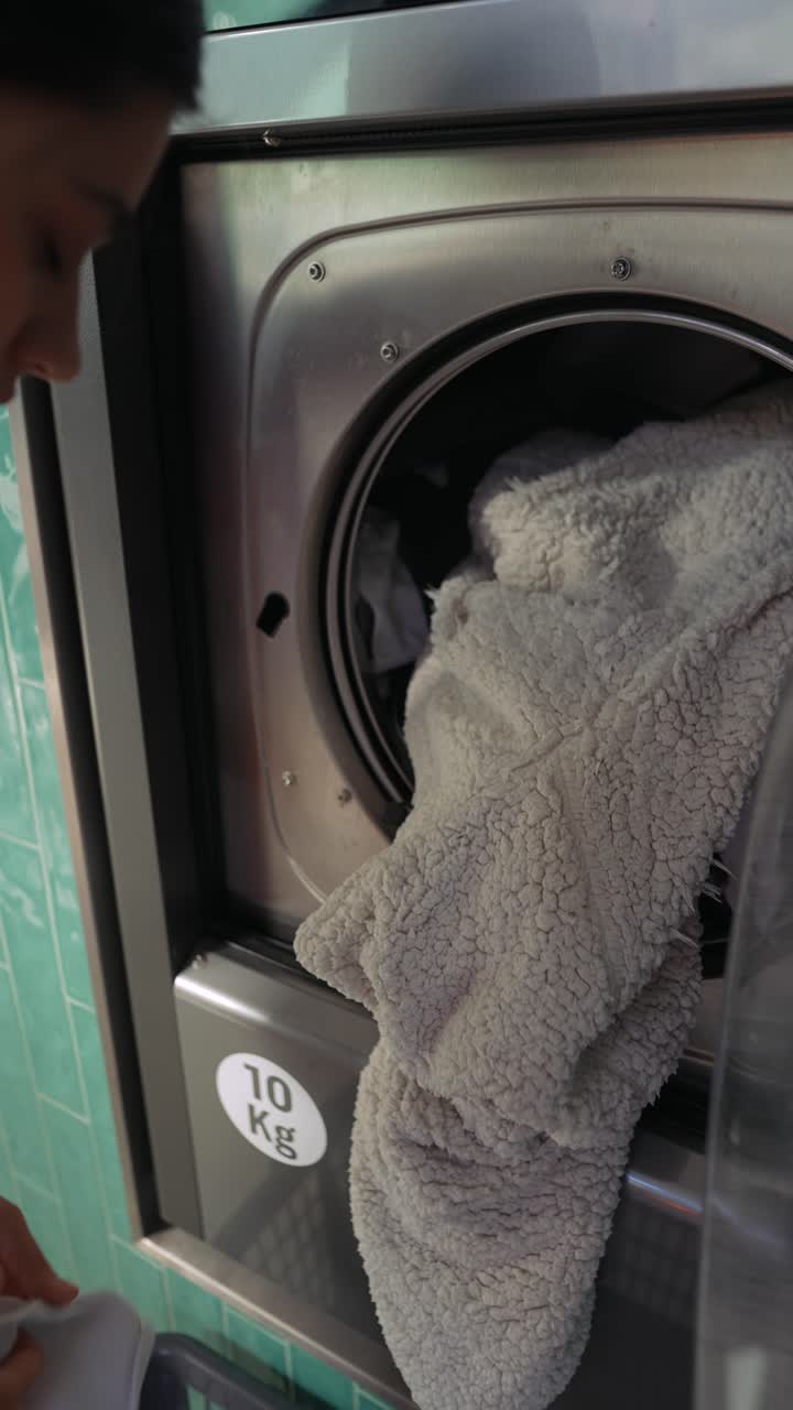 Woman loading clothes into a commercial washing machine