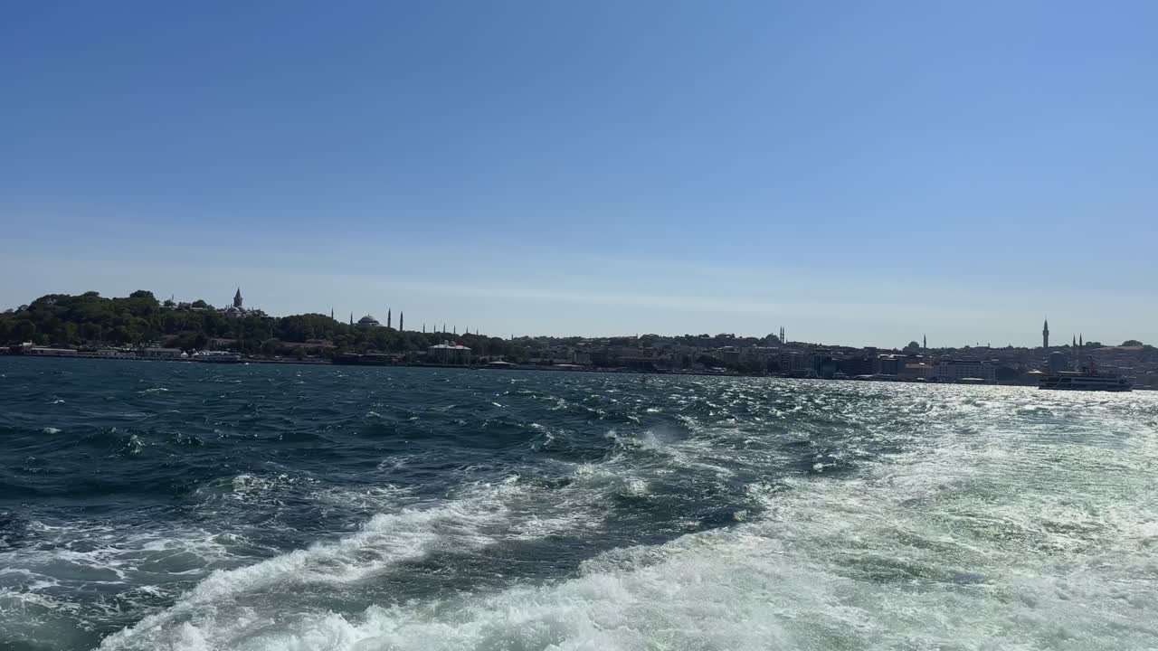 Boat cruising forward over choppy blue ocean waves, foamy wake behind