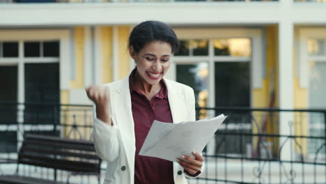 una orgullosa mujer de negocios examinando documentos afuera.