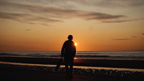 Man-running-with-guitar-in-back-sand-beach-at-sunset