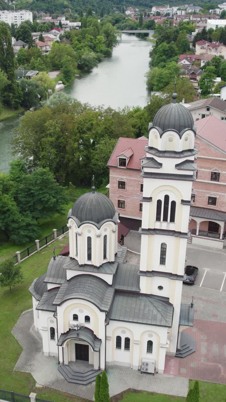 Aerial view of a Serbian Orthodox church in Banja Luka, Bosnia and Herzegovina, highlighting its domes, bell tower, and surrounding landscape. Vertical Video