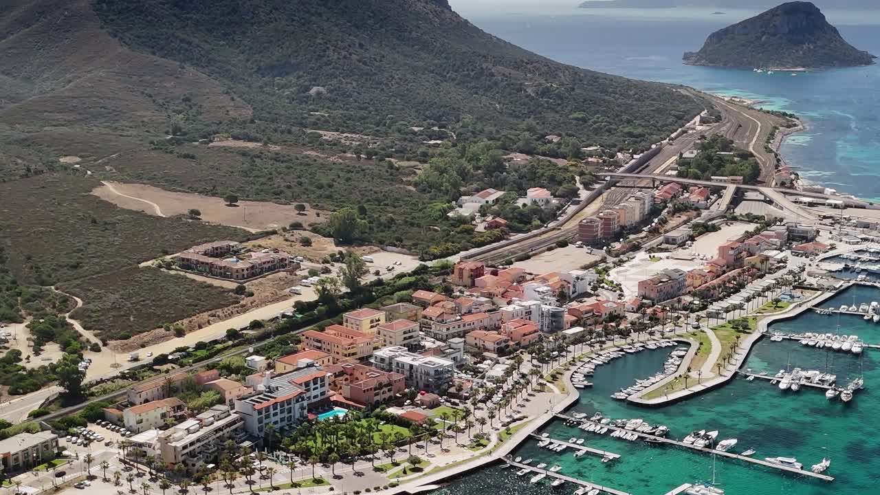 Cittadina costiera sarda con barche e colline sullo sfondo