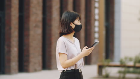 asian woman in mask using phone on street