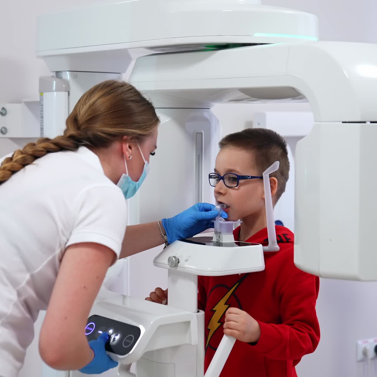 Esame radiografico con moderne attrezzature avanzate in cliniche odontoiatriche. Un'infermiera regola l'apparecchio per un bambino piccolo. Primo piano
