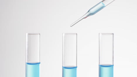 video of glass laboratory test tubes and pipette with blue liquid and copy space on white background