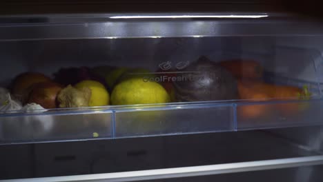 Woman-hand-opening-and-closing-fridge-door,-grabbing-a-yellow-citrus-fruit