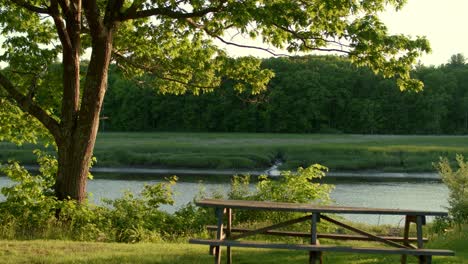 drone bajo empujando hacia adelante sobre una mesa de picnic y girando sobre el río durante la hora dorada en stratham, nh cerca de exeter