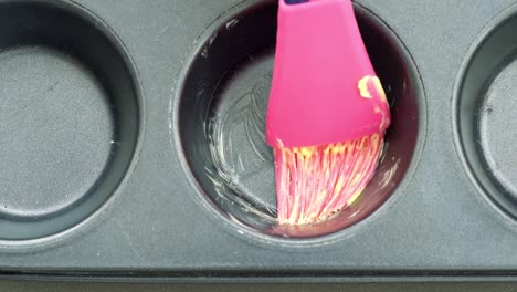 someone smearing butter on the mold