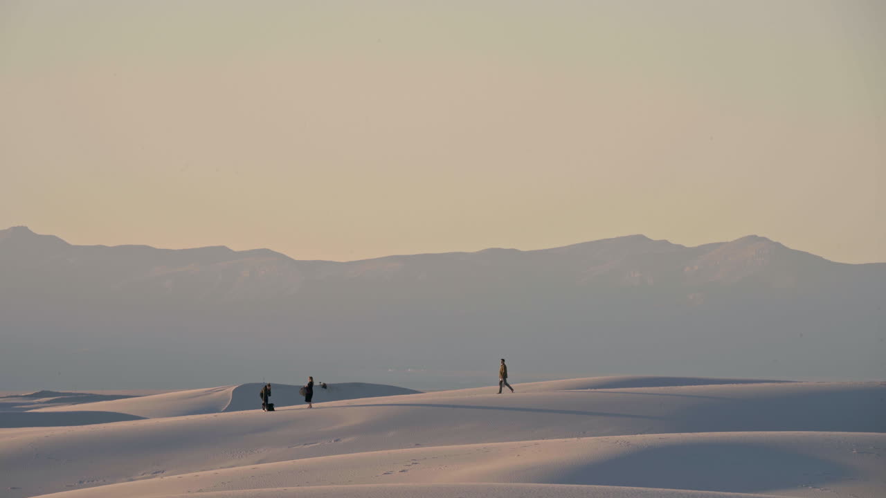 하얀 모래 언덕에서 일몰 피크닉을 준비하는 방문자의 망원 보기, 4k