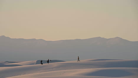 Vista-De-Teleobjetivo-De-Los-Visitantes-Que-Preparan-Un-Picnic-Al-Atardecer-En-Las-Dunas-De-Arena-Blanca,-4k