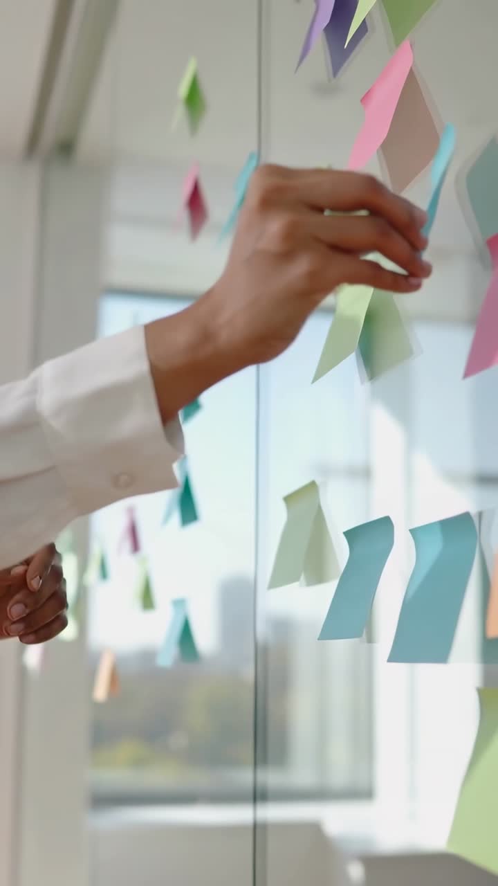 Vídeo vertical: Mão alinhando post-its em vidro no escritório para planejamento, manga branca