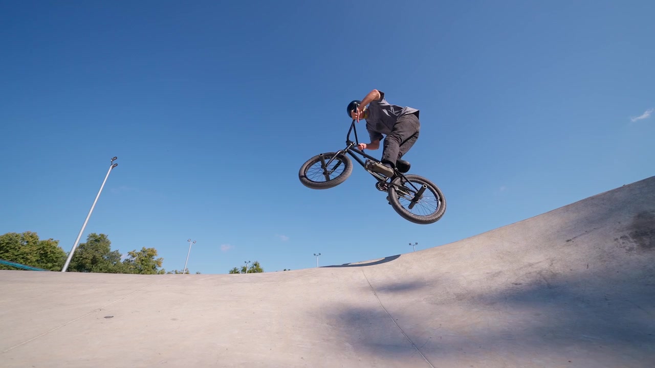 Giovane uomo in BMX che esegue un trick manuale nello skatepark