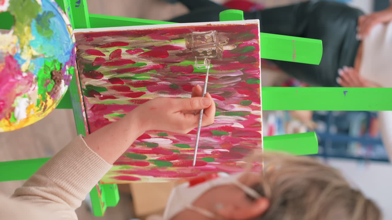A woman painting a picture using a palette and brush in a studio