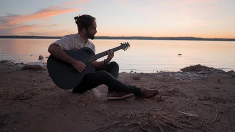 man playing guitar at sunset on the beach