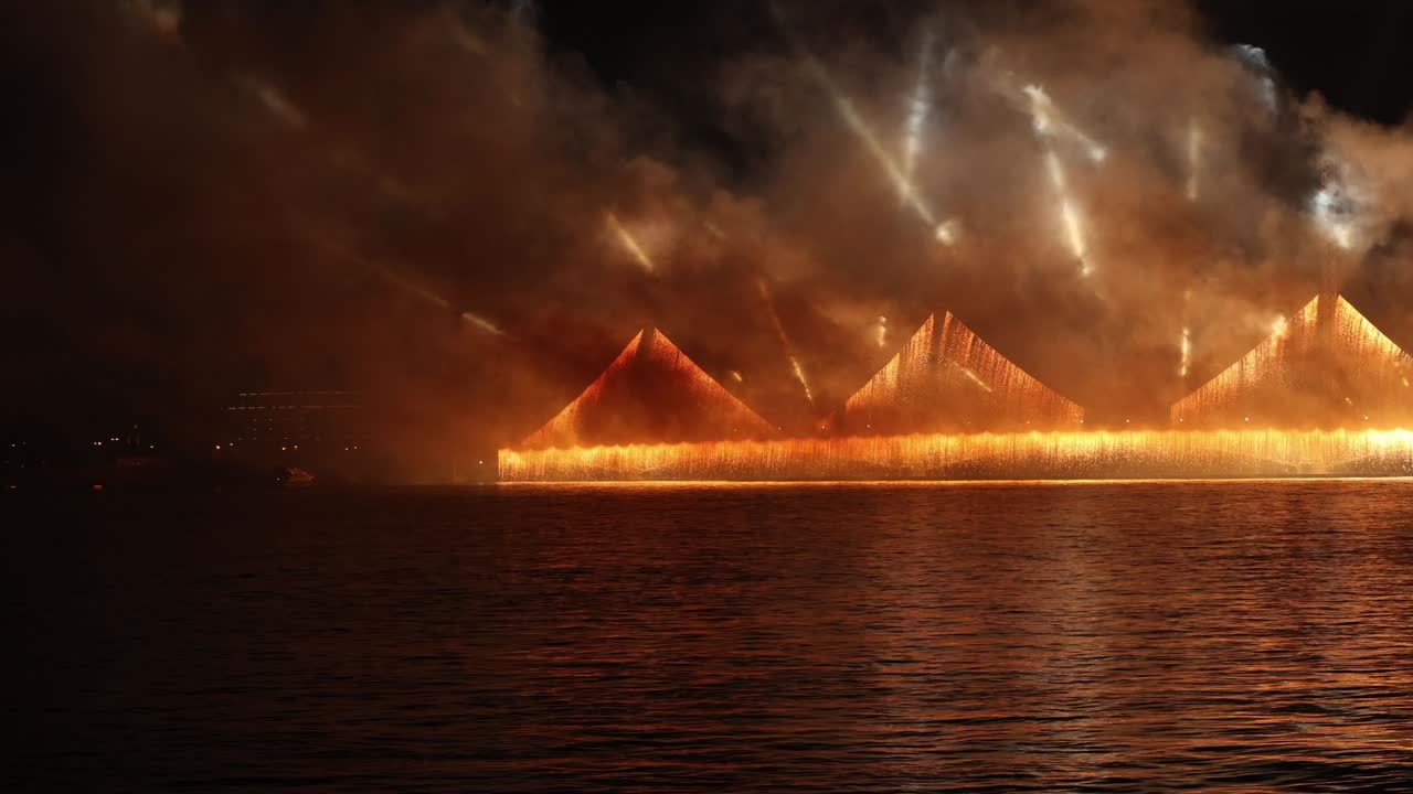 어두운 하늘에서 화려한 반사와 함께 화려한 불꽃놀이와 밝은 빛이 물 속에 아름답게 반사됩니다.