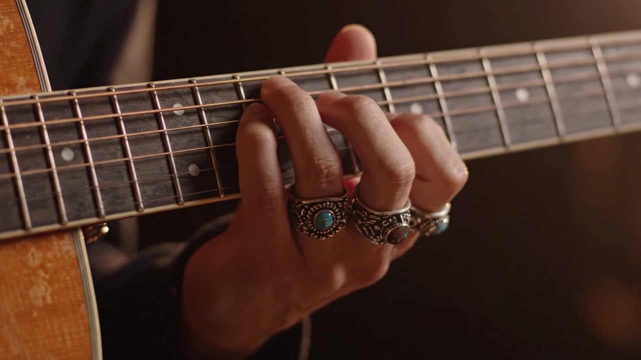 Primo piano di una mano che strimpella una chitarra, catturando l'arte e l'emozione nella creazione musicale, focalizzato sul posizionamento delle dita e sui dettagli dello strumento.