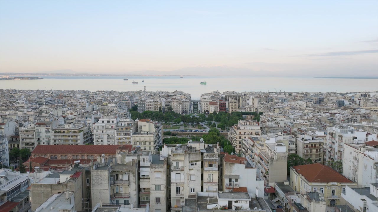 Panorama aereo dell'espansione urbana di Salonicco che conduce al Golfo Termaico, con navi visibili sulle calme acque costiere.