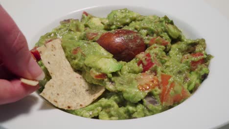 El-Chip-De-Tortilla-Se-Rompe-En-La-Mano-Sacando-Guacamole-Del-Tazón,-Cerrado