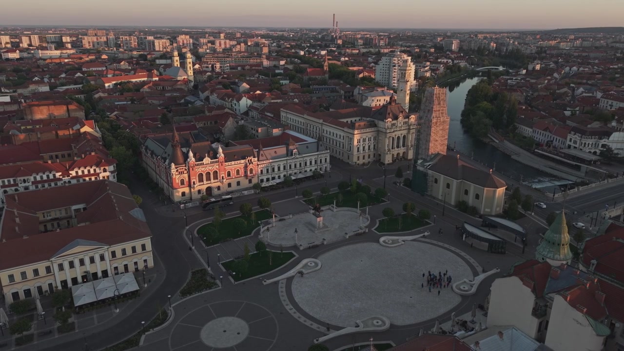 Eine Luftaufnahme per Drohne von einem historischen europäischen Stadtzentrum mit einem großen runden Platz, umgeben von eleganten Gebäuden und Kirchen.