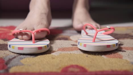 Woman's Feet in Pink Striped Flip-Flops on a Carpet