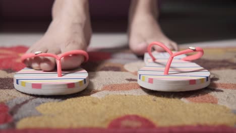 los pies de la mujer en zapatillas rosadas a rayas en una alfombra