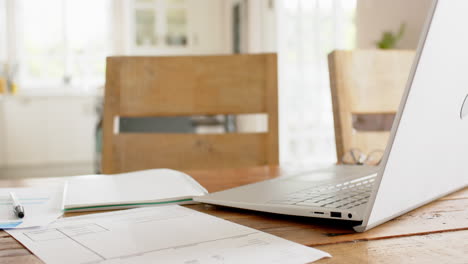 papelería, sartén y portátil en la mesa en una habitación soleada en casa, cámara lenta