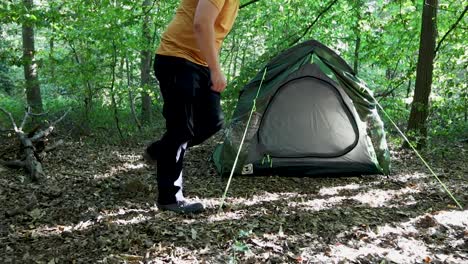 person adjusting tent while camping forest area, back view