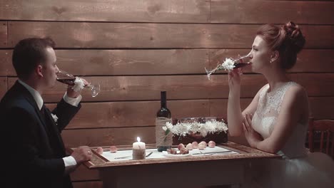 Young-couple-sitting-in-restaurant-at-table-and-drinking-wine