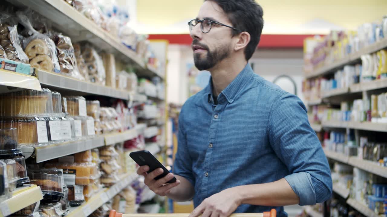 hombre usando un teléfono inteligente en el supermercado
