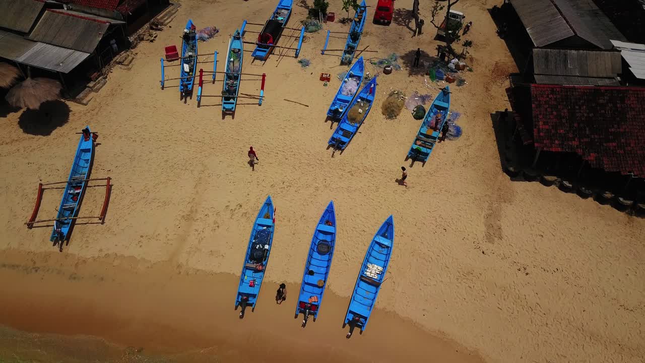 toma aérea de arriba hacia abajo de muchos barcos de pesca en una playa de arena en indonesia