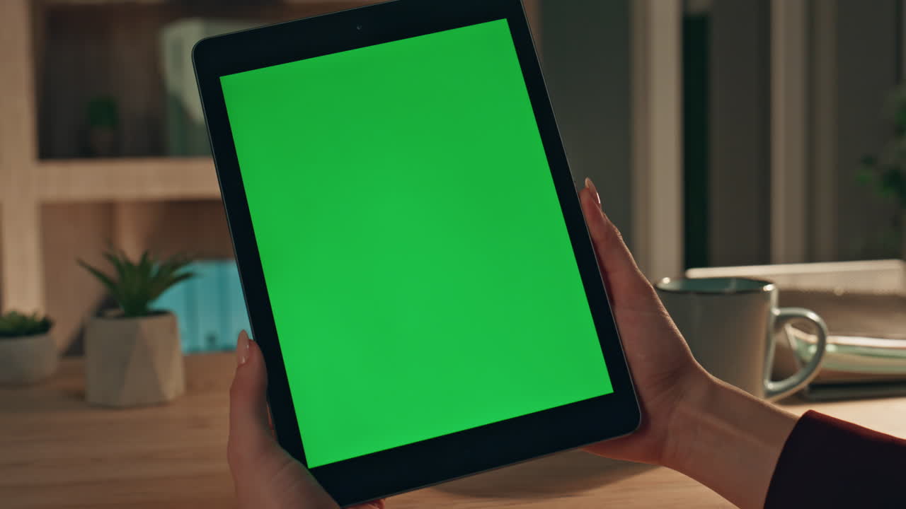 Online worker browsing chroma key tablet application at evening office closeup.