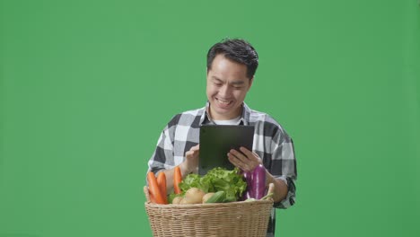 hombre usando una tableta para ver una canasta de verduras