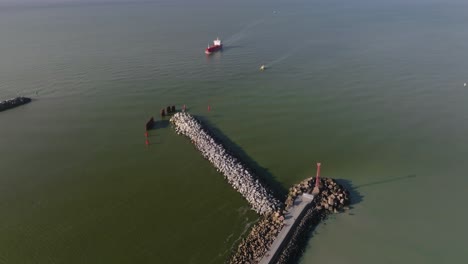 aerial view  a red cargo ship is about to enter the port from the baltic sea through the port gate